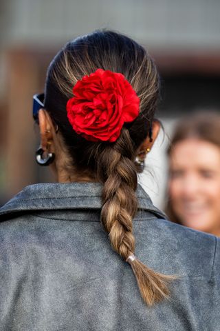 Brunette woman with red flower hair accessory and plait GettyImages-1978362111