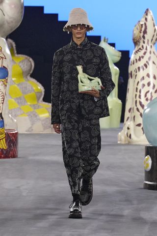 Dior Men S/S 2025 look on runway featuring model holding ceramic