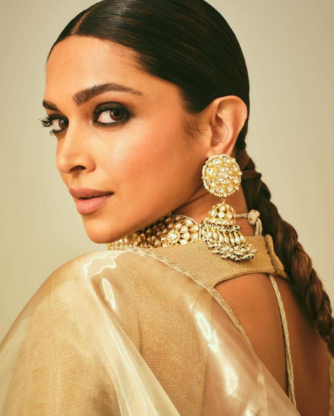 Deepika chose a large motif jhumka (traditional Indian earring) and a choker necklace. Her sleek mid-part hairstyle, styled in neat, low ponytail braids, completed her stunning look.