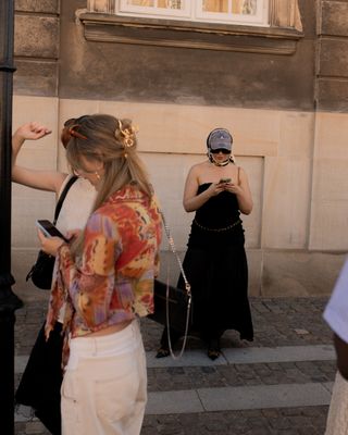 a guest at copenhagen fashion week stands outside the shows wearing a clear claw clip and white pants