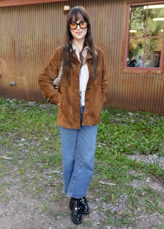 Dakota Johnson wears a brown suede jacket with jeans and black boots