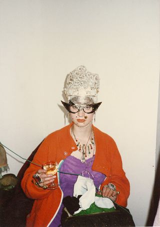 Nicola Tyson in a red cardigan glasses and wig